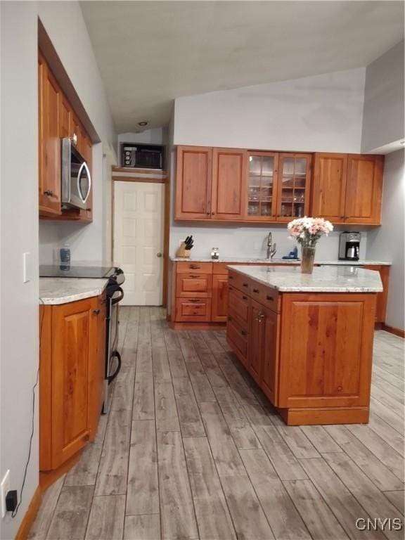 kitchen featuring light hardwood / wood-style floors, a kitchen island, range with electric cooktop, and vaulted ceiling