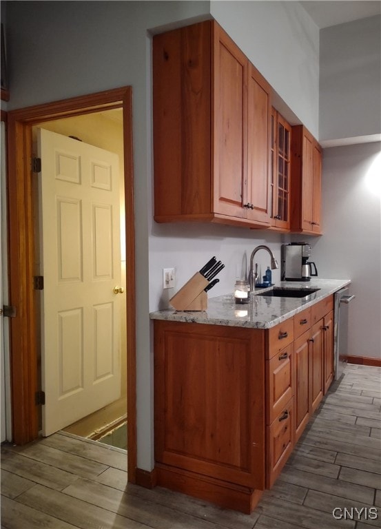 kitchen with light stone countertops, sink, and light hardwood / wood-style flooring