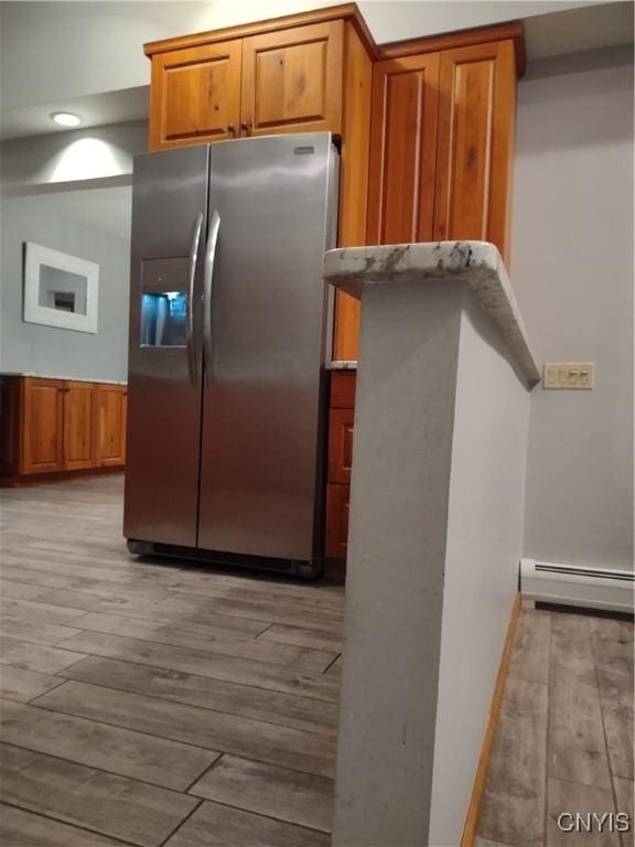 kitchen with light hardwood / wood-style floors, a baseboard heating unit, and stainless steel fridge