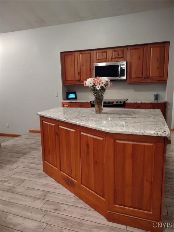 kitchen with a center island, light stone countertops, stainless steel appliances, and light hardwood / wood-style flooring