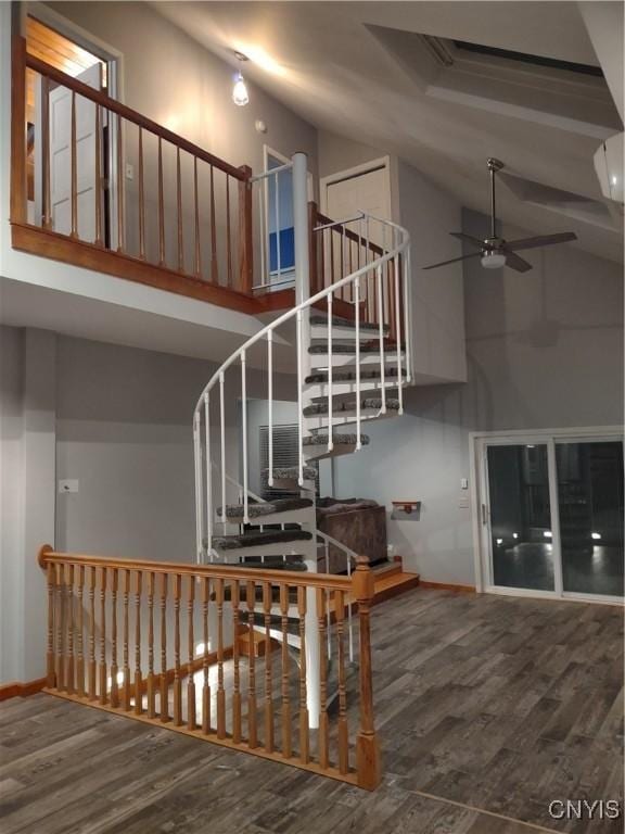 stairs with high vaulted ceiling, ceiling fan, and hardwood / wood-style floors