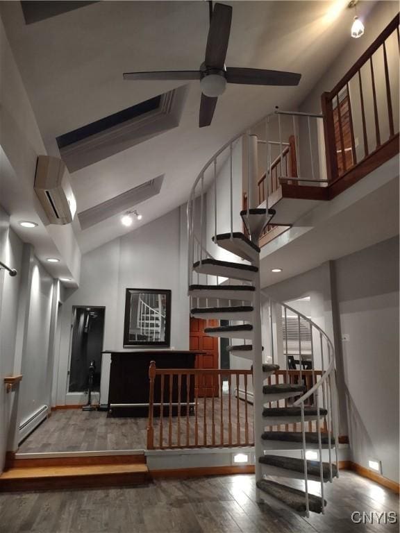 stairs with ceiling fan, a baseboard radiator, hardwood / wood-style floors, and a wall mounted air conditioner