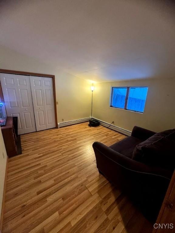 living room with a baseboard heating unit and light hardwood / wood-style flooring