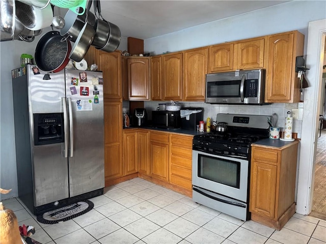 kitchen with appliances with stainless steel finishes, backsplash, and light tile patterned flooring