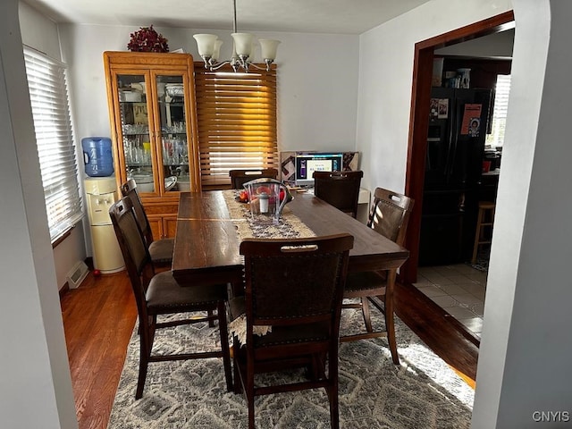 dining space with wood-type flooring and an inviting chandelier