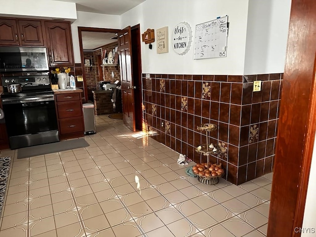 kitchen featuring dark brown cabinets, stainless steel appliances, and tile walls