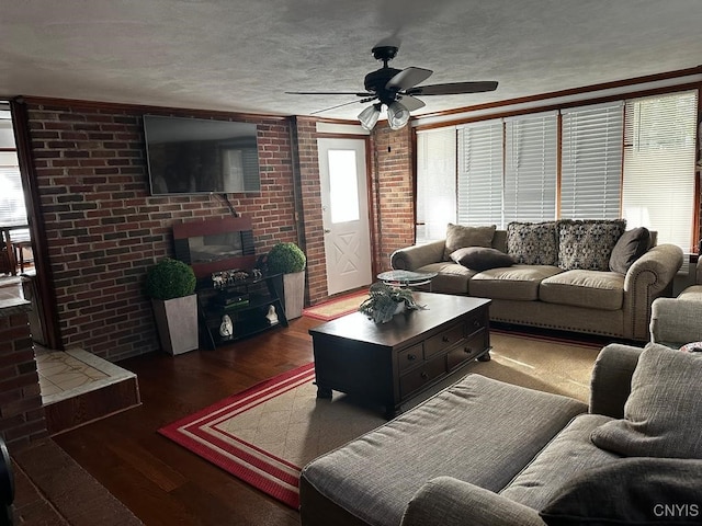 living room with crown molding, ceiling fan, a textured ceiling, dark hardwood / wood-style flooring, and brick wall