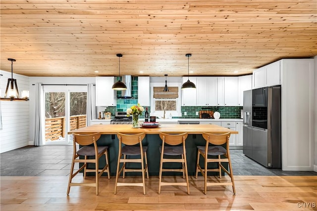 kitchen featuring wooden ceiling, pendant lighting, white cabinets, and stainless steel fridge