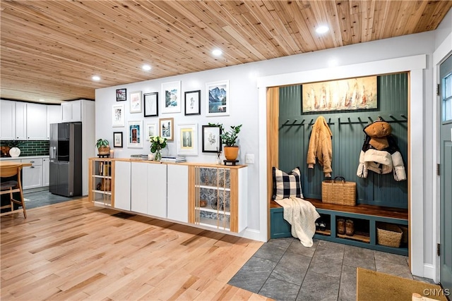 interior space with white cabinets, decorative backsplash, wooden ceiling, and stainless steel refrigerator with ice dispenser