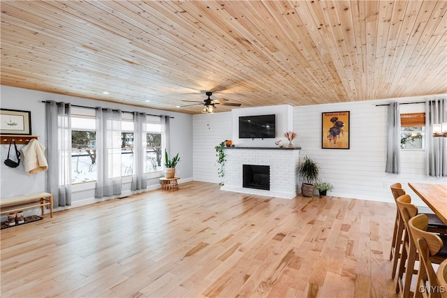 living room featuring a fireplace, wood walls, ceiling fan, and wood ceiling