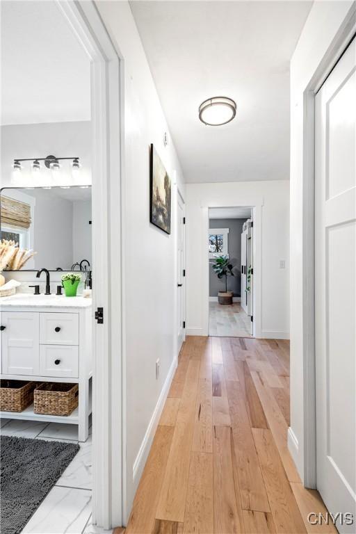 hallway with light hardwood / wood-style flooring and sink