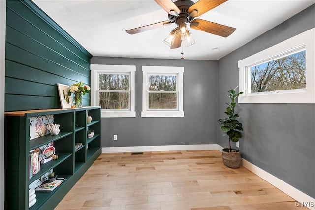 sitting room with light hardwood / wood-style floors, a healthy amount of sunlight, and wooden walls