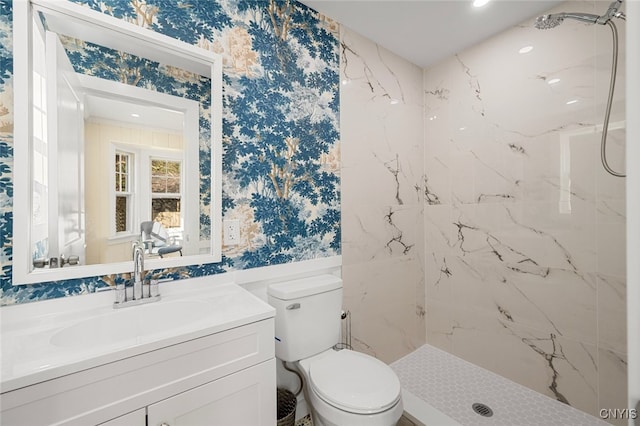 bathroom with tiled shower, vanity, and toilet