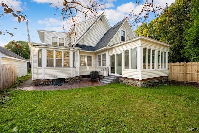 rear view of house with a sunroom, cooling unit, and a yard