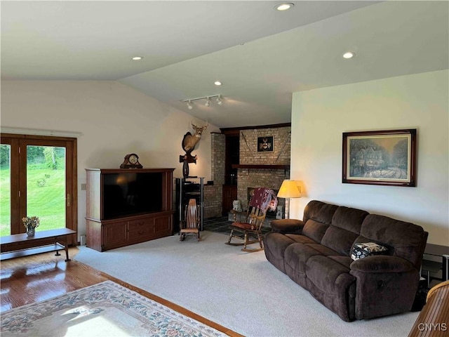 living room featuring a fireplace, rail lighting, light hardwood / wood-style floors, and lofted ceiling