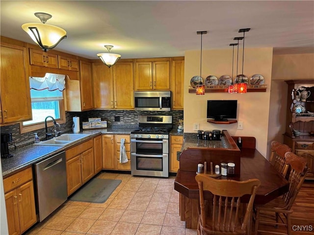 kitchen featuring sink, backsplash, pendant lighting, light tile patterned floors, and appliances with stainless steel finishes