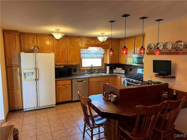 kitchen with appliances with stainless steel finishes, tasteful backsplash, sink, decorative light fixtures, and light tile patterned flooring