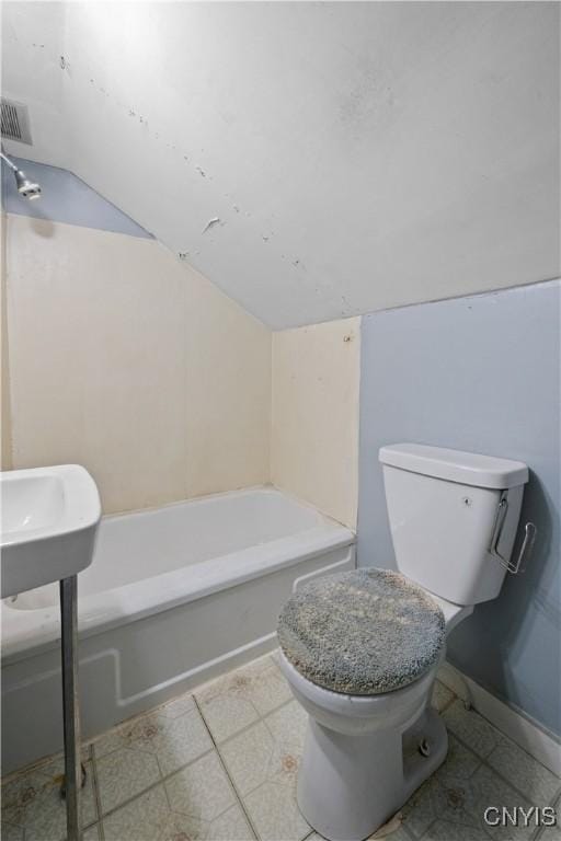 bathroom with toilet, a tub to relax in, and vaulted ceiling