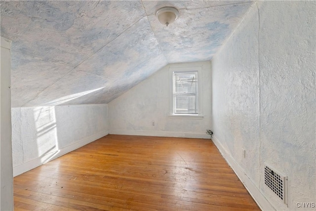 additional living space with wood-type flooring and lofted ceiling