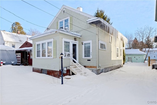 snow covered house featuring a garage and an outdoor structure