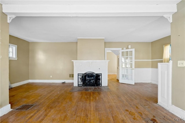 unfurnished living room with hardwood / wood-style flooring and a brick fireplace