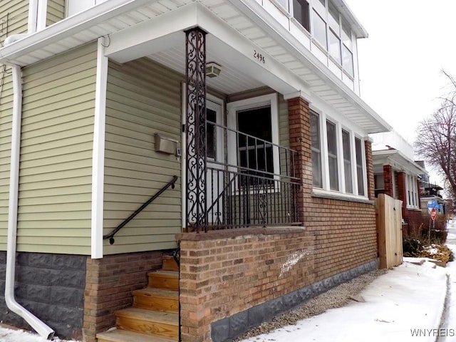 view of snowy exterior featuring covered porch