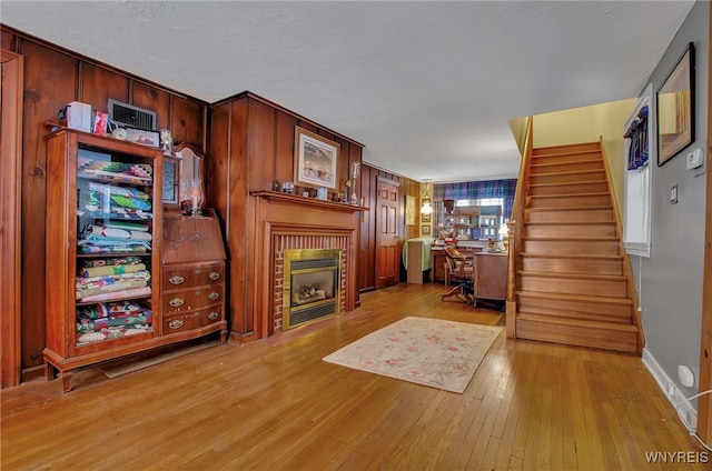 home office with light hardwood / wood-style floors, a brick fireplace, and wooden walls