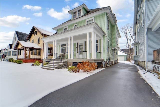 view of front of house with a porch, a garage, and an outbuilding