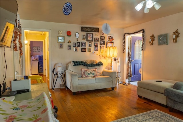 living room featuring ceiling fan and dark hardwood / wood-style floors