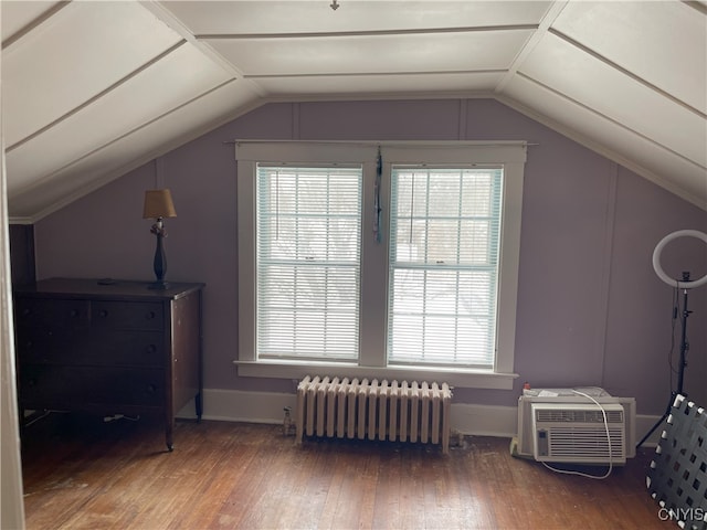 bonus room featuring a wall unit AC, hardwood / wood-style floors, radiator heating unit, and lofted ceiling