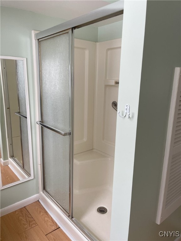 bathroom featuring a shower with shower door and wood-type flooring