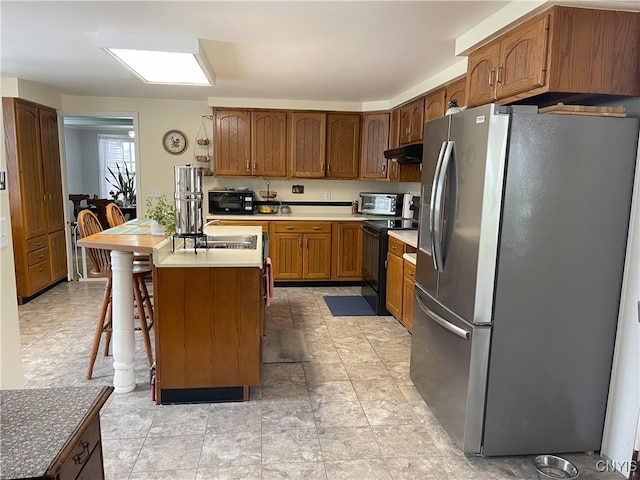 kitchen with black appliances, sink, a kitchen breakfast bar, and a kitchen island