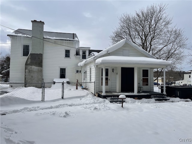 snow covered back of property featuring covered porch