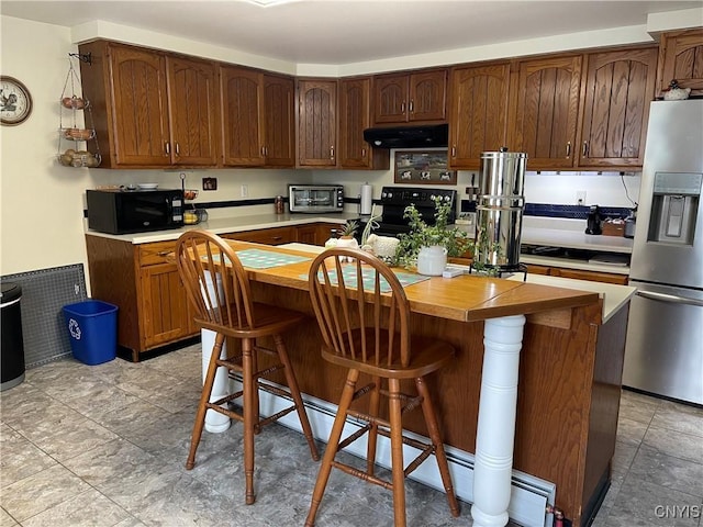 kitchen with a baseboard heating unit, a breakfast bar area, ventilation hood, a kitchen island, and black appliances