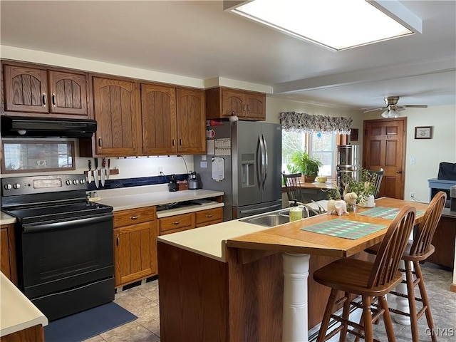 kitchen featuring stainless steel fridge with ice dispenser, ceiling fan, a kitchen breakfast bar, range hood, and black electric range oven