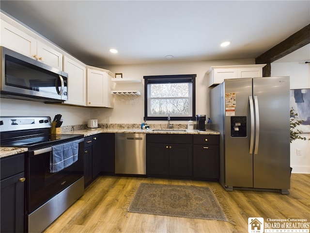 kitchen featuring sink, white cabinets, light wood-type flooring, and appliances with stainless steel finishes