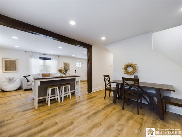 dining space featuring beamed ceiling and light hardwood / wood-style flooring