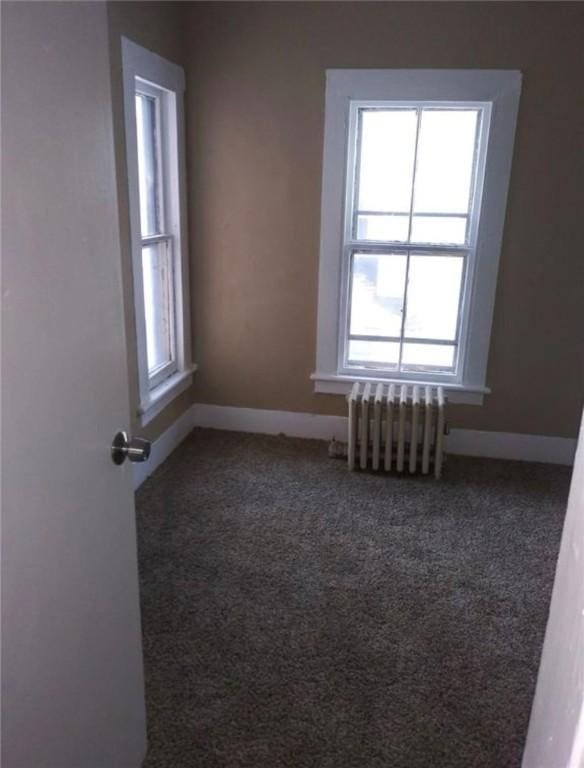 unfurnished room with radiator and carpet floors