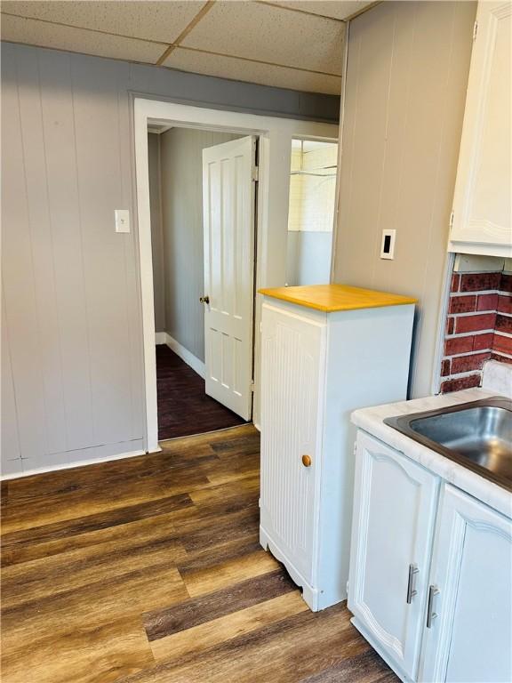 kitchen featuring white cabinets, a drop ceiling, and dark hardwood / wood-style flooring