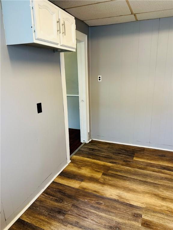 interior space featuring white cabinets, dark hardwood / wood-style floors, and a drop ceiling