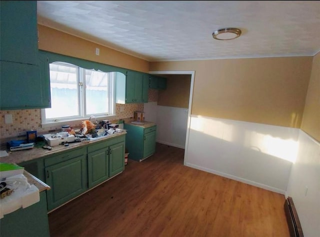 kitchen with sink, green cabinetry, tasteful backsplash, dark hardwood / wood-style flooring, and a baseboard radiator