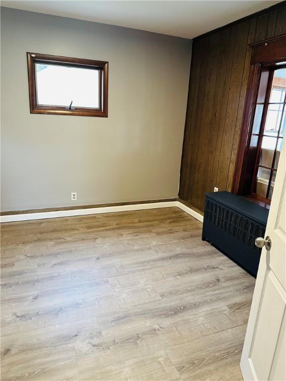 empty room with wood walls and light hardwood / wood-style flooring