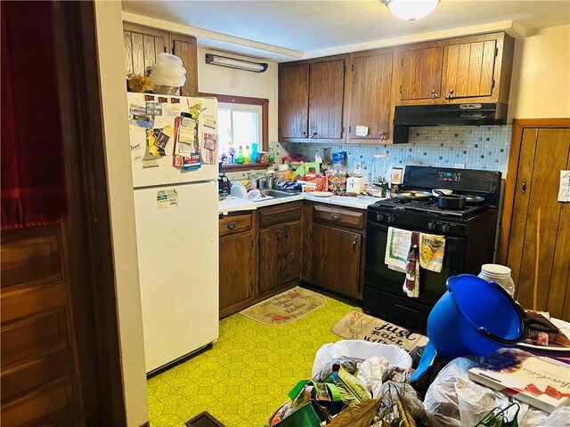 kitchen featuring black gas range, backsplash, sink, and white refrigerator