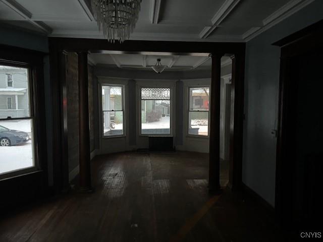 interior space featuring a healthy amount of sunlight, dark hardwood / wood-style floors, coffered ceiling, and a chandelier