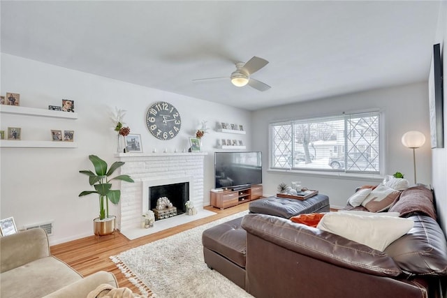 living room with ceiling fan, a fireplace, and hardwood / wood-style floors