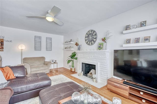 living room featuring ceiling fan, a fireplace, and hardwood / wood-style flooring