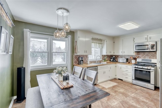 kitchen featuring decorative light fixtures, white cabinetry, and stainless steel appliances