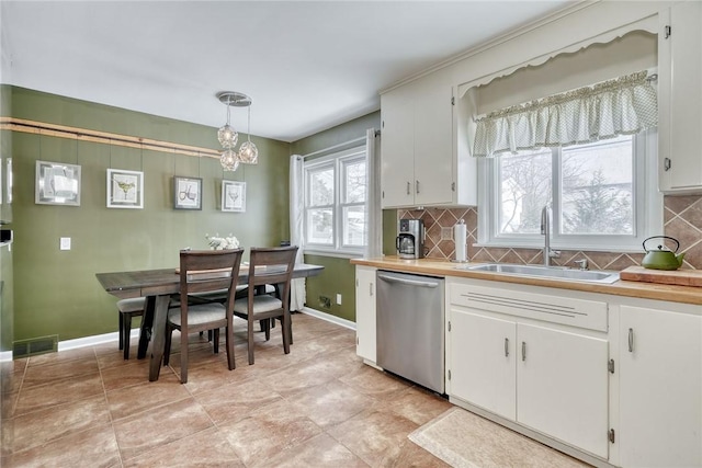 kitchen with dishwasher, sink, hanging light fixtures, tasteful backsplash, and white cabinets