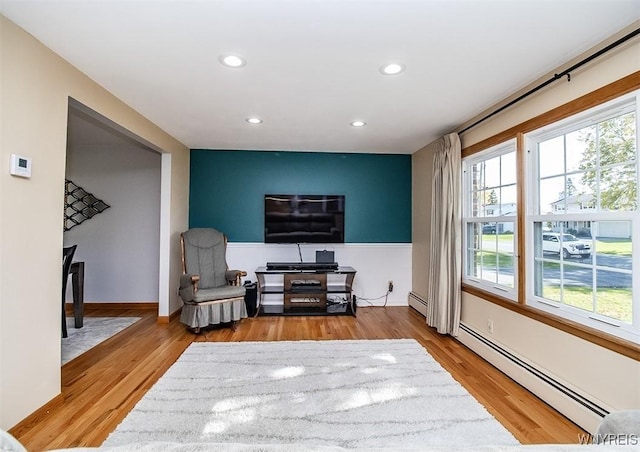 living room with wood-type flooring and a baseboard heating unit