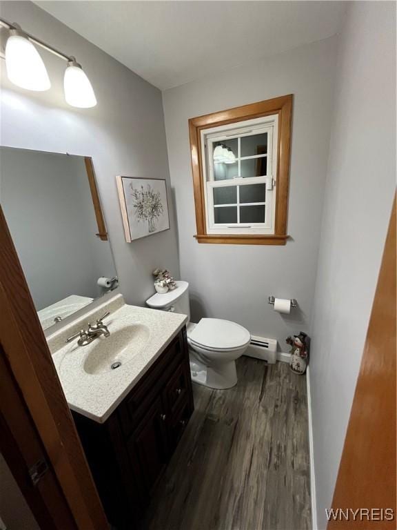 bathroom with hardwood / wood-style flooring, vanity, toilet, and baseboard heating